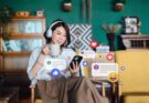 beautiful-young-asian-woman-with-headphones-relaxing-at-home-and-using-smartphone-checking-social-media
