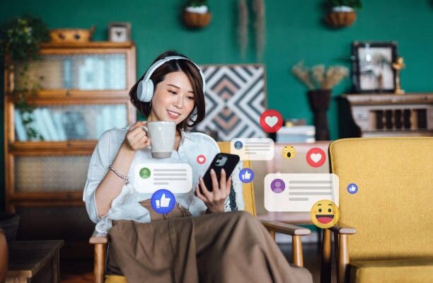 beautiful-young-asian-woman-with-headphones-relaxing-at-home-and-using-smartphone-checking-social-media